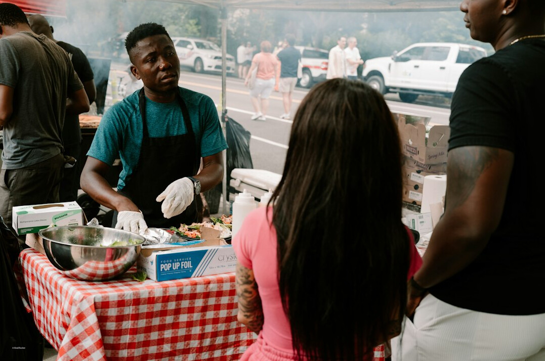 People standing in line at an outdoor food market stall