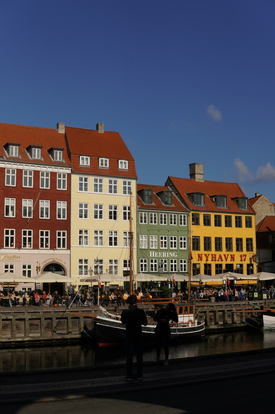 Colorful harbour houses in Nyhavn, Copenhagen with people walking along the quay